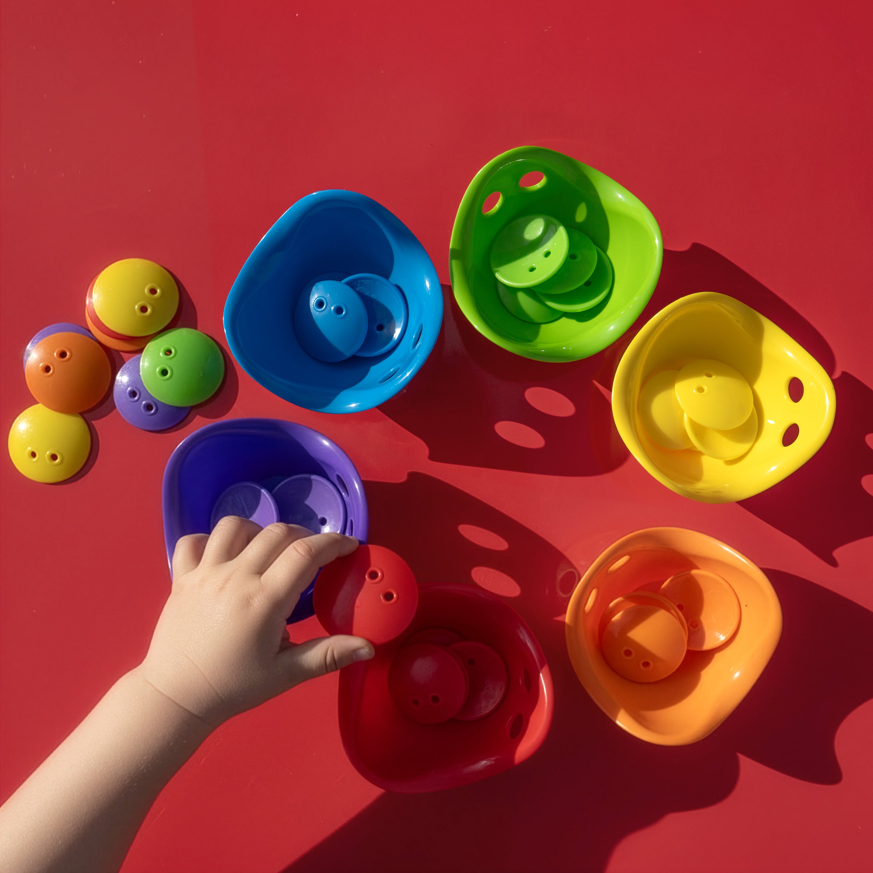 Child sorting Bilibo Dots by color into Bilibo Mini shells – open-ended learning play by MOLUK