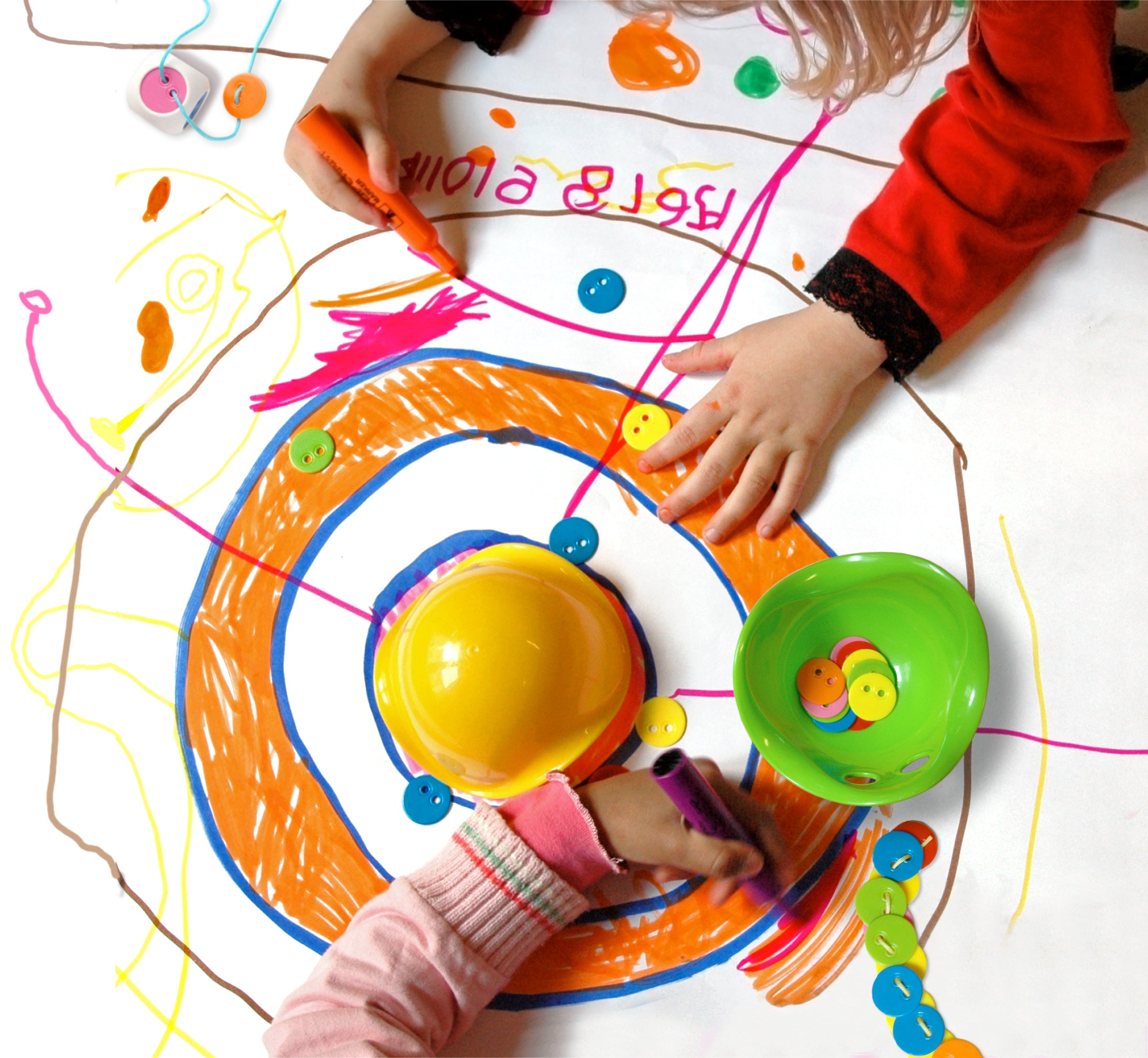 Children drawing and playing with the Bilibo Game Box by MOLUK, using colorful chips and Mini Bilibo shells on a large hand-drawn play mat.