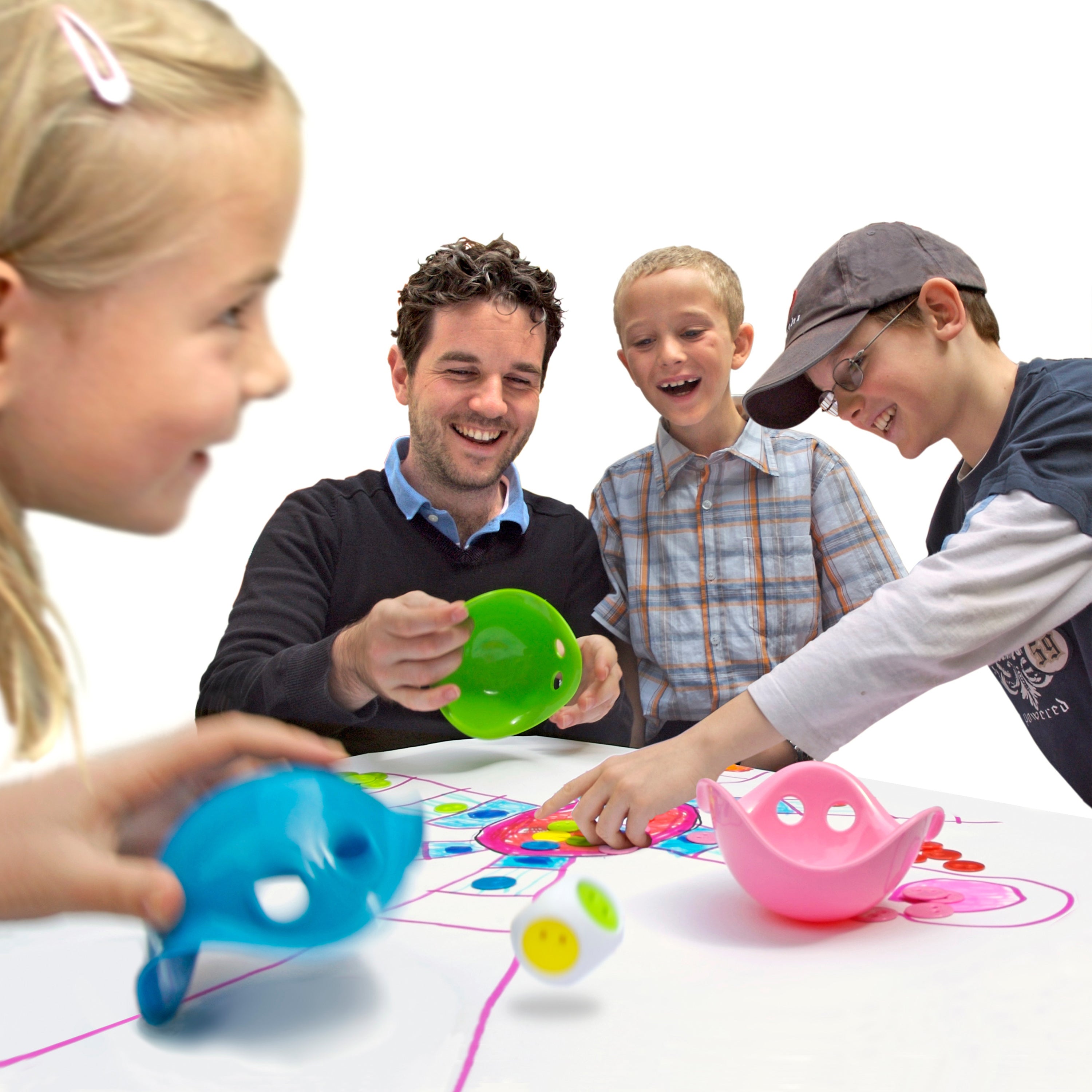 Children and adult playing together with the Bilibo Game Box by MOLUK, using colorful Mini Bilibos, chips, and a dice on a hand-drawn game board.