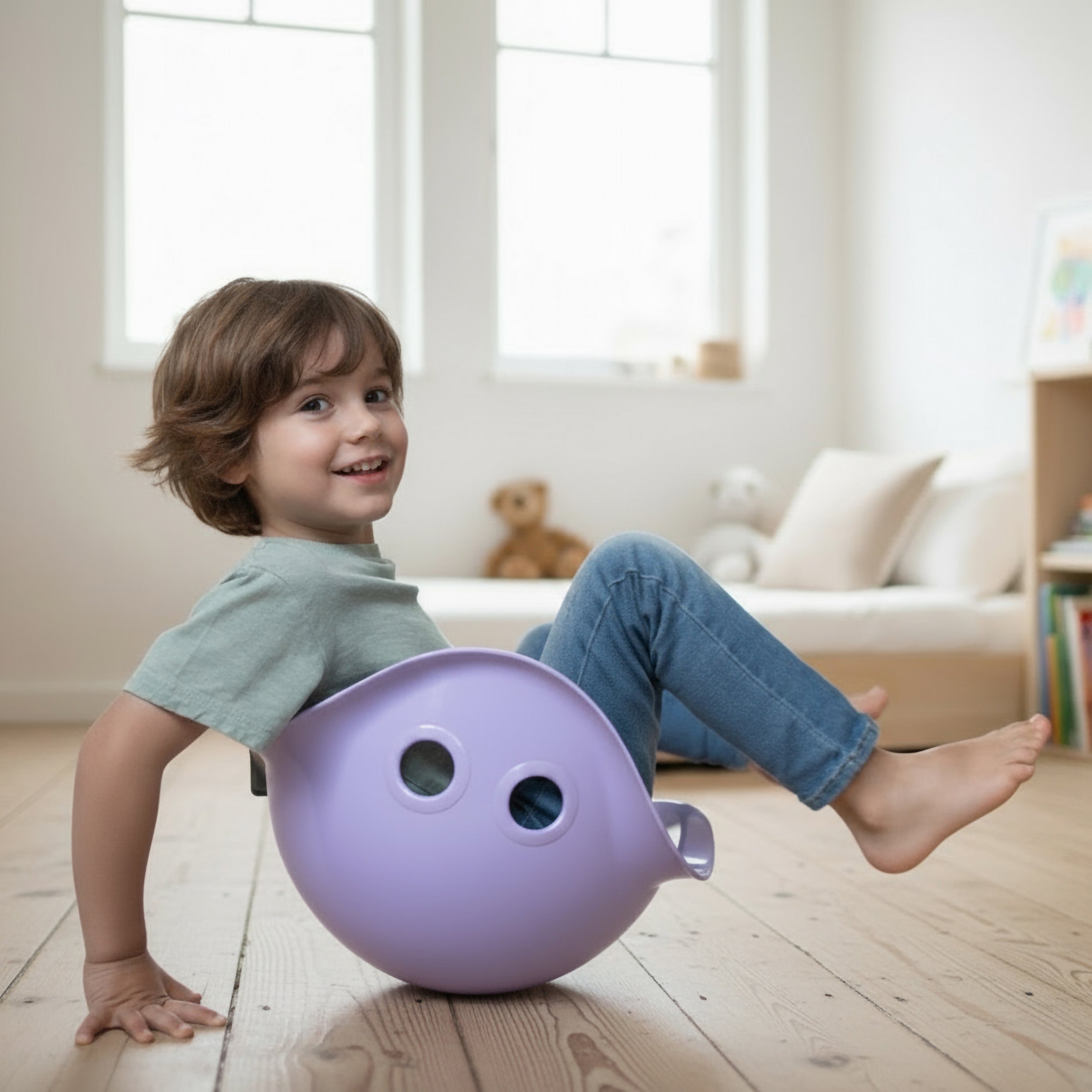5-year-old boy balancing in a lilac Bilibo rocking and spinning seat by MOLUK in a bright, Montessori-inspired children’s room.