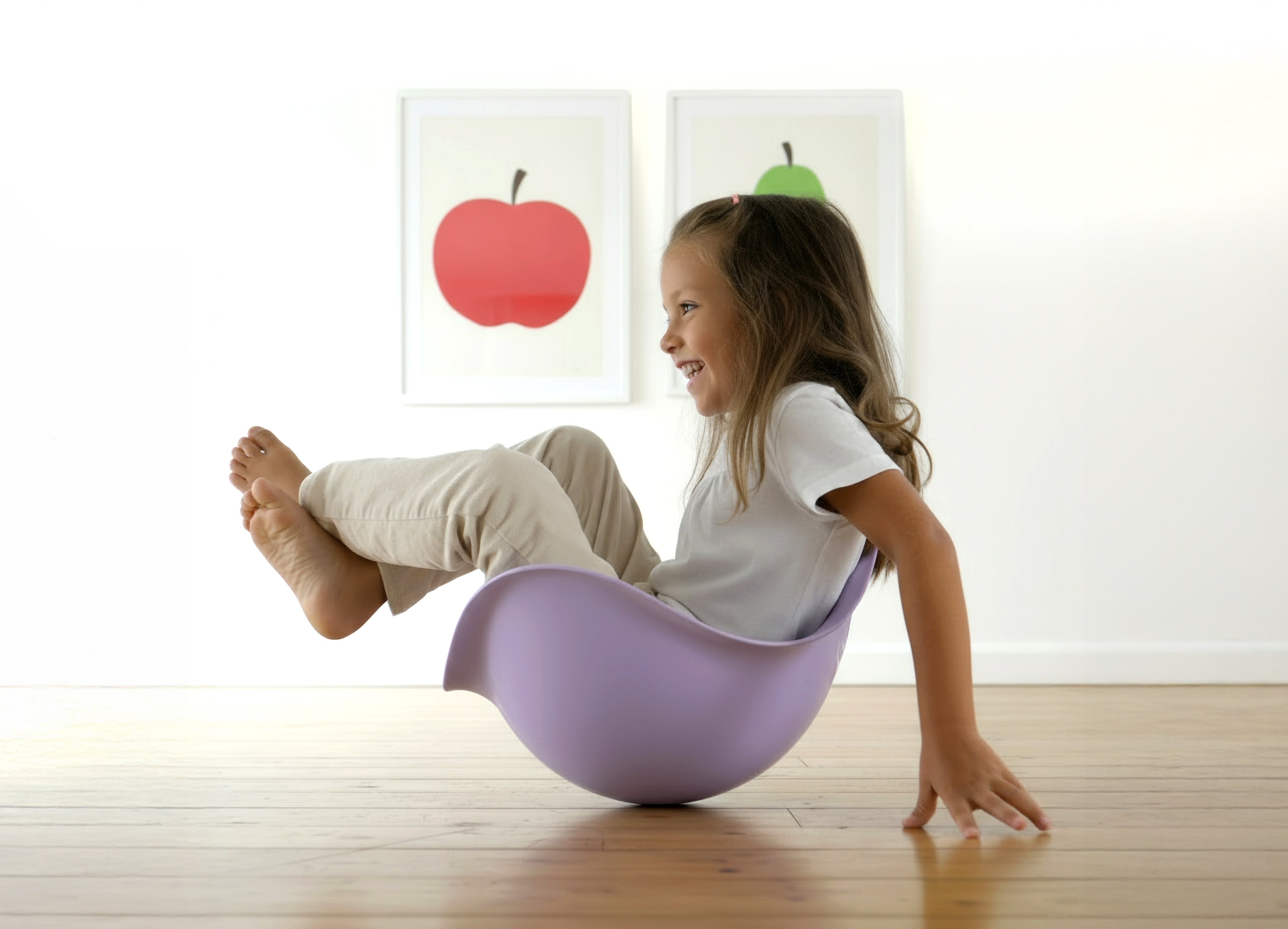 Girl sitting and balancing inside a lilac Bilibo by MOLUK in a modern children’s room, exploring open-ended movement play.
