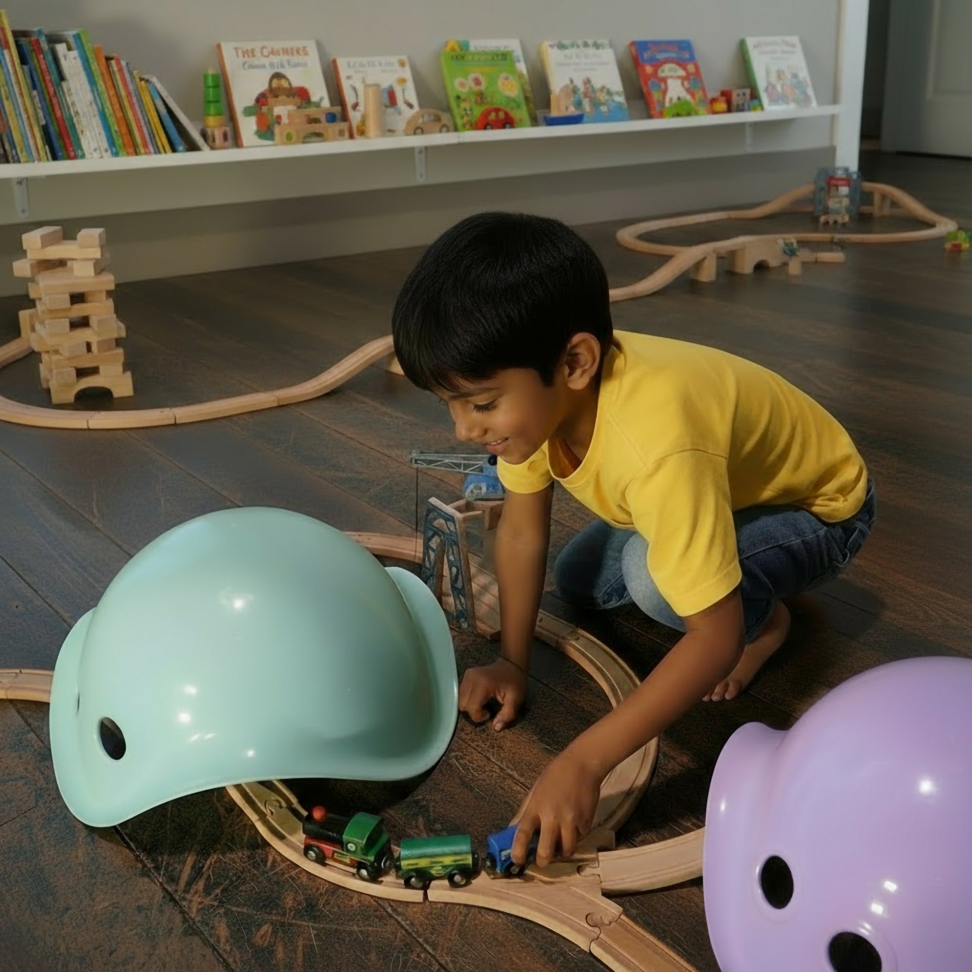 5-year-old boy playing with a wooden toy train set using mint and lilac Bilibo open-ended play shells by MOLUK as mountains and tunnels.