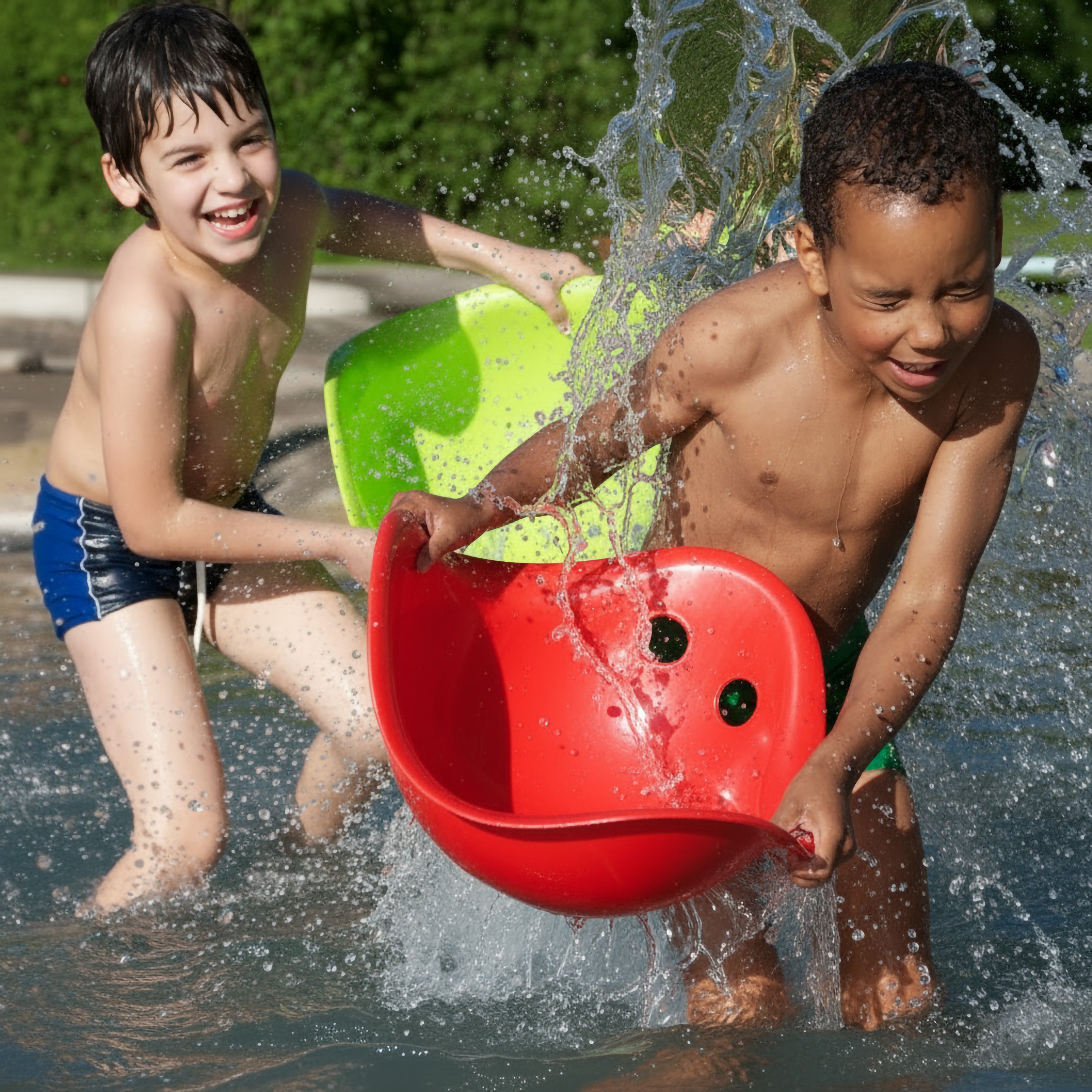 Two boys playing in the pool, splashing water with a red and a green Bilibo play shell by MOLUK.
