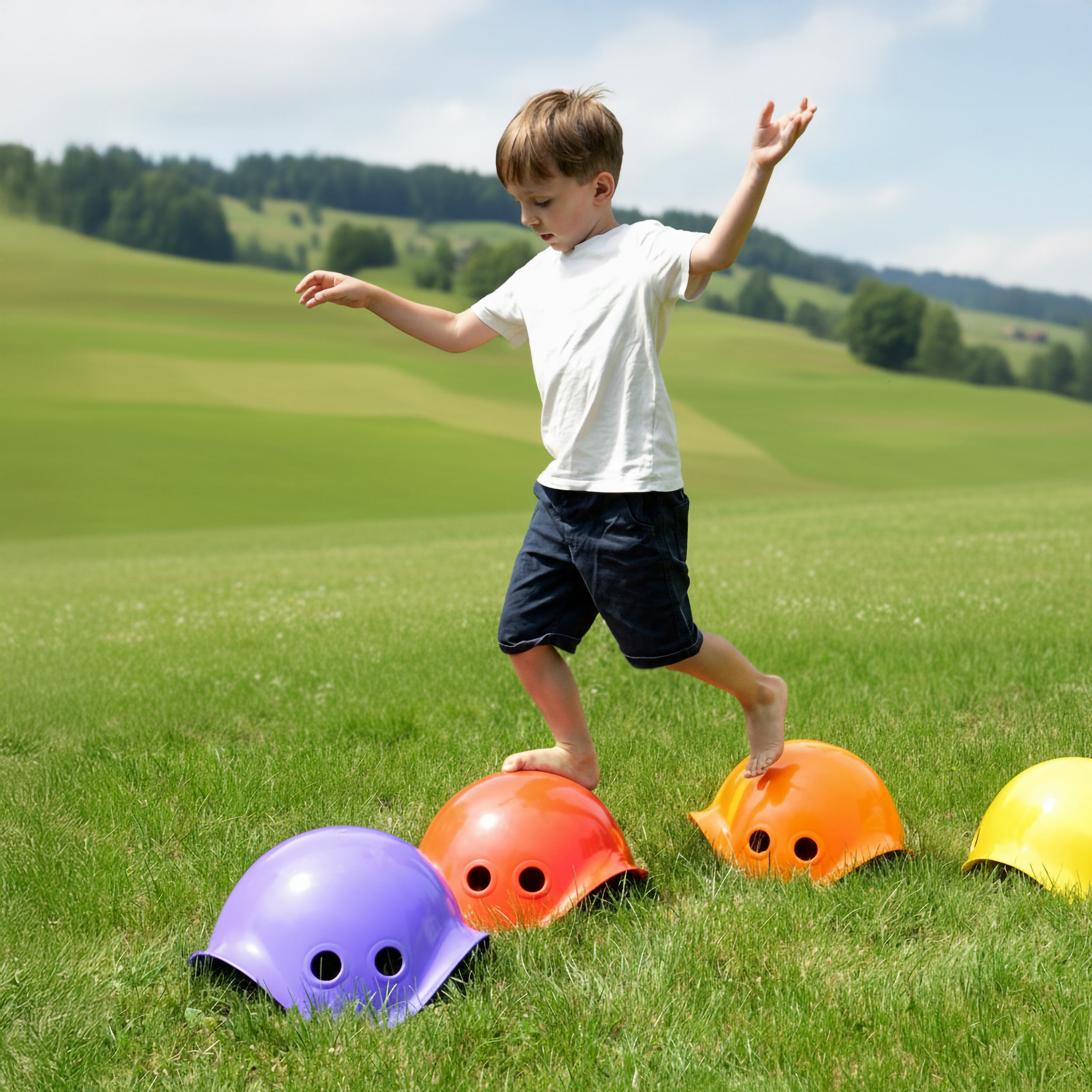 Boy balancing on colorful Bilibo stepping stones by MOLUK, on a grass field in the Swiss countryside.
