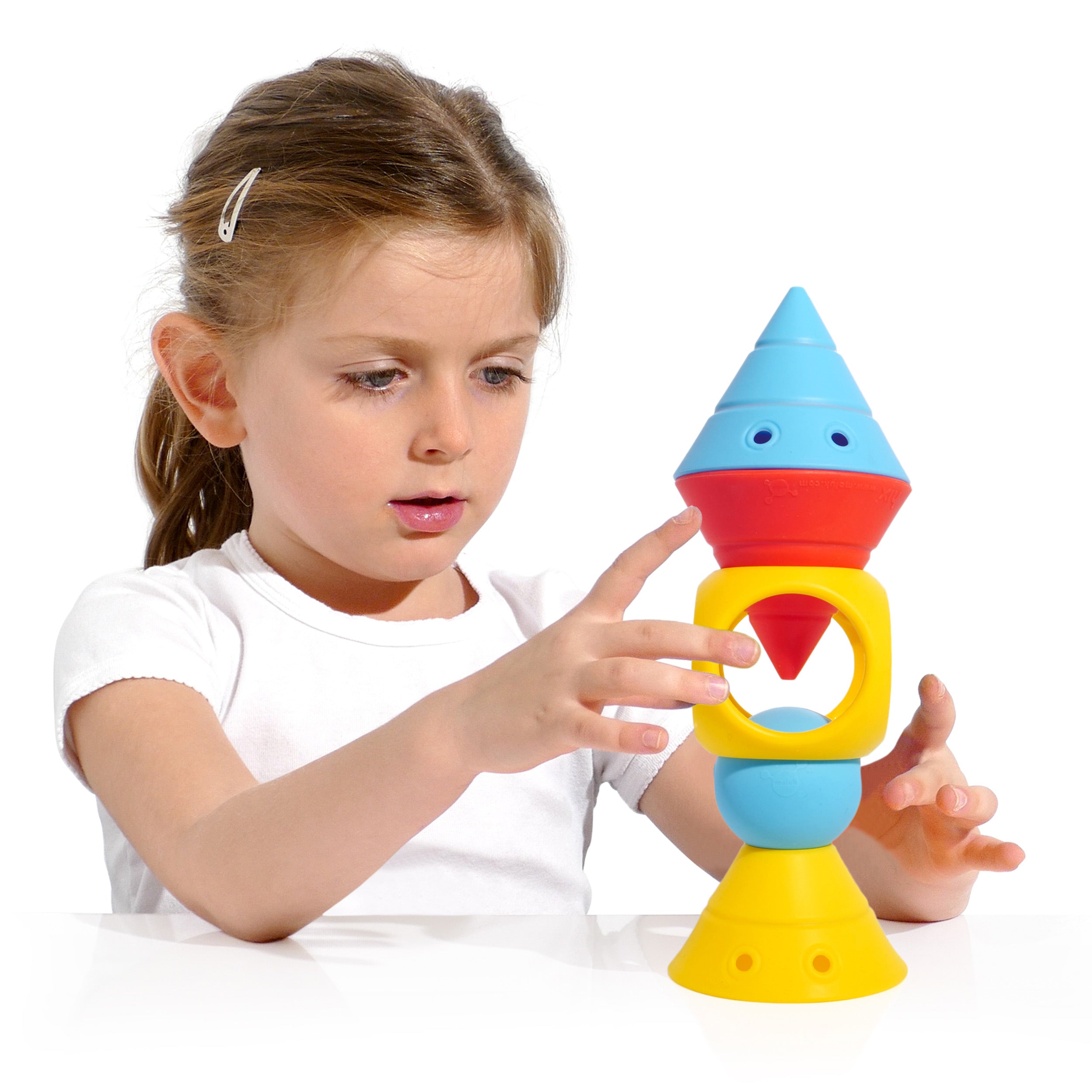 Girl building a tower with the BUILDING GENIUS set by MOLUK, stacking Hix cones, Mox balls, and Oibo blocks in bright primary colors.