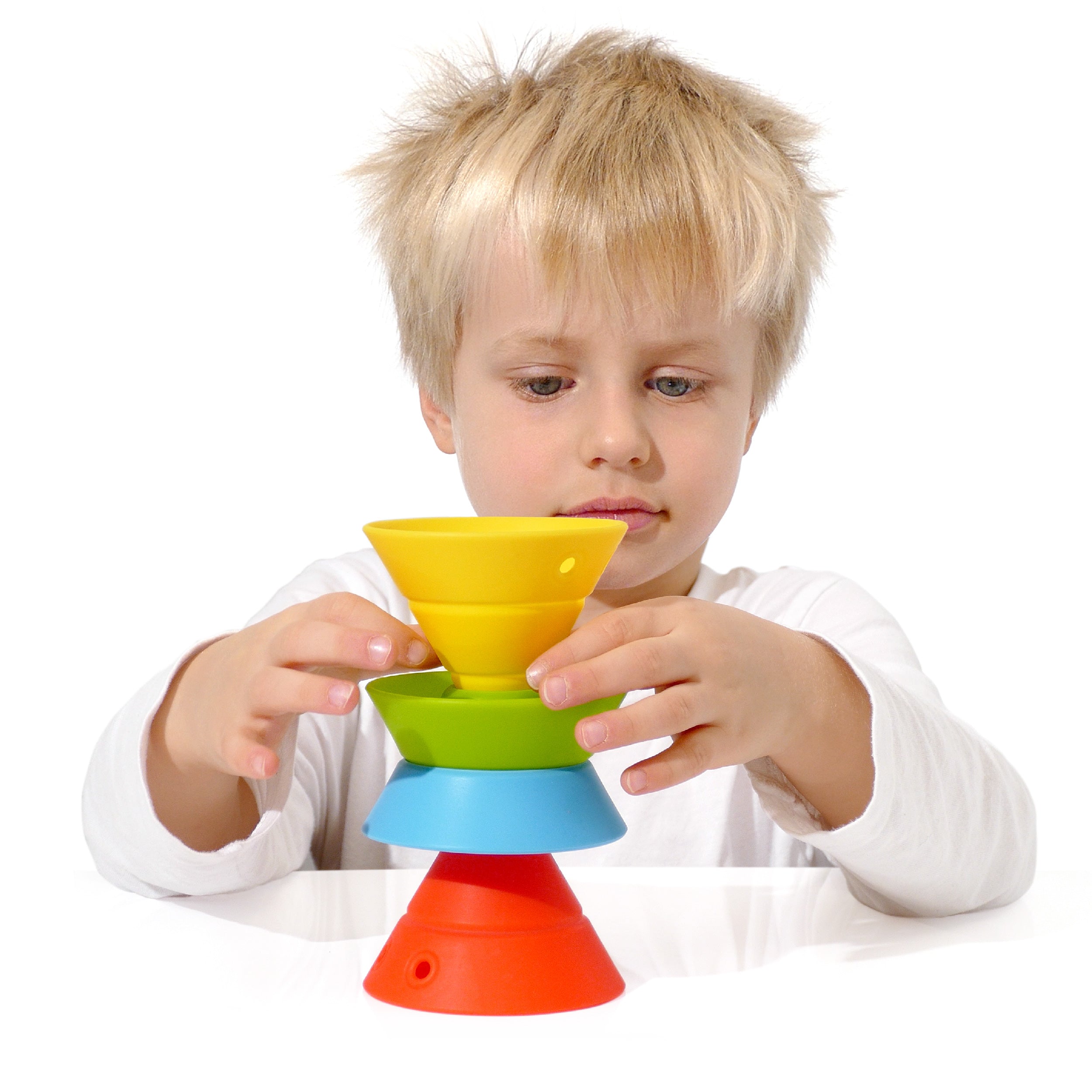 Boy building a tower with a set of convertible Hix silicone construction cones by MOLUK in primary colors.