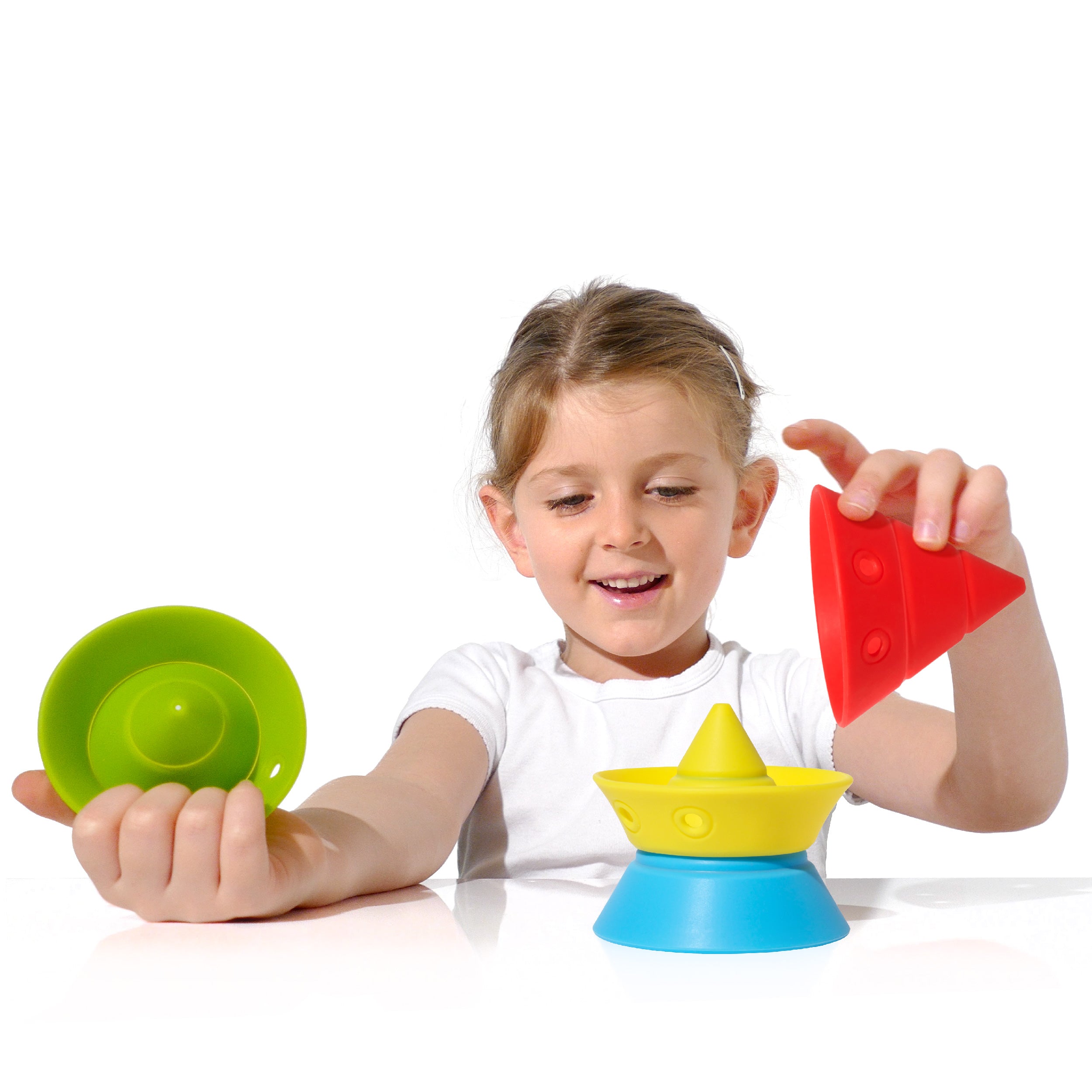 Girl playing with a set of convertible Hix silicone construction cones by MOLUK in primary colors, stacking and nesting the pieces.