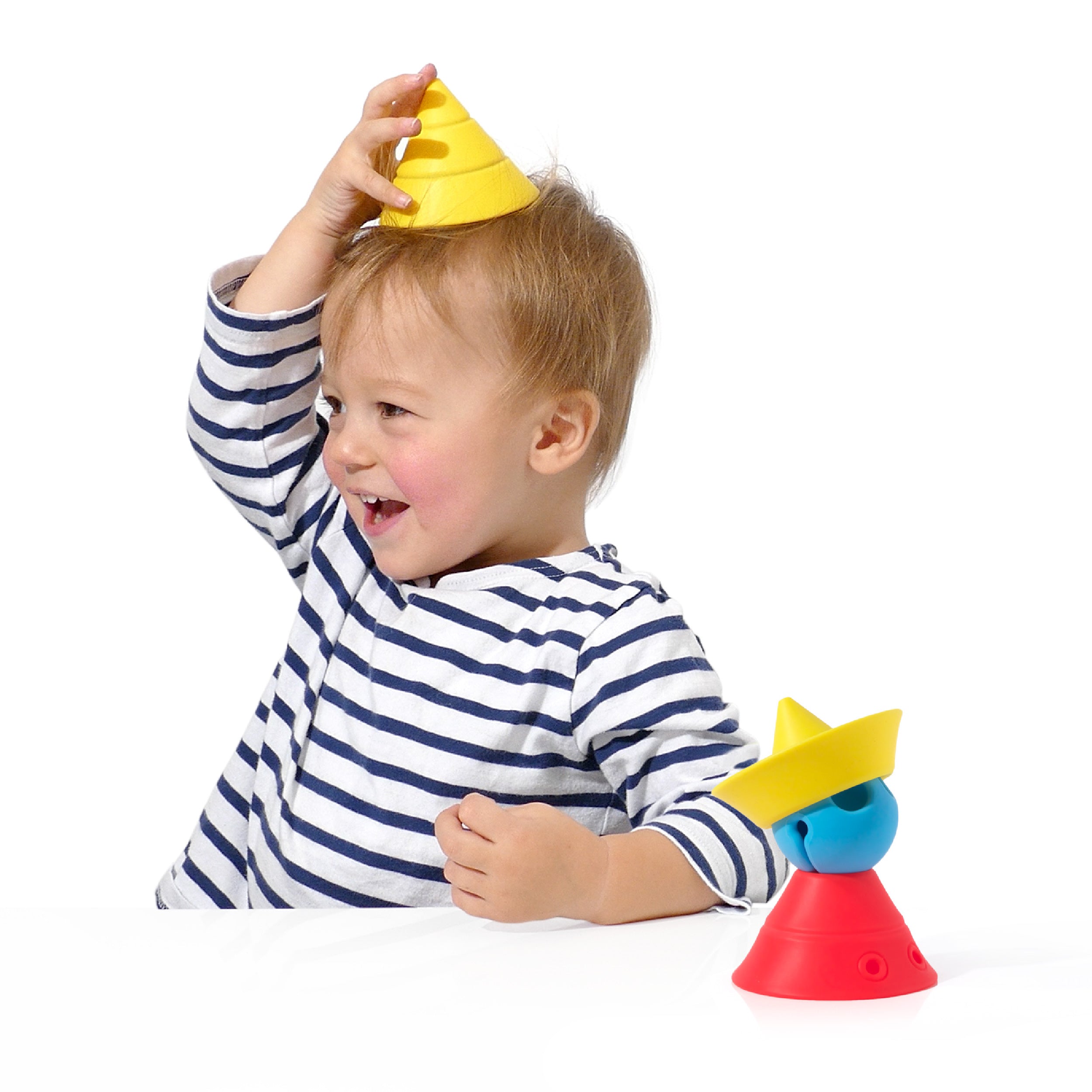 Childing playing with the open-ended Hix silicone sensory cones by MOLUK, wearing a yellow Hix cone like a hat in pretend play.