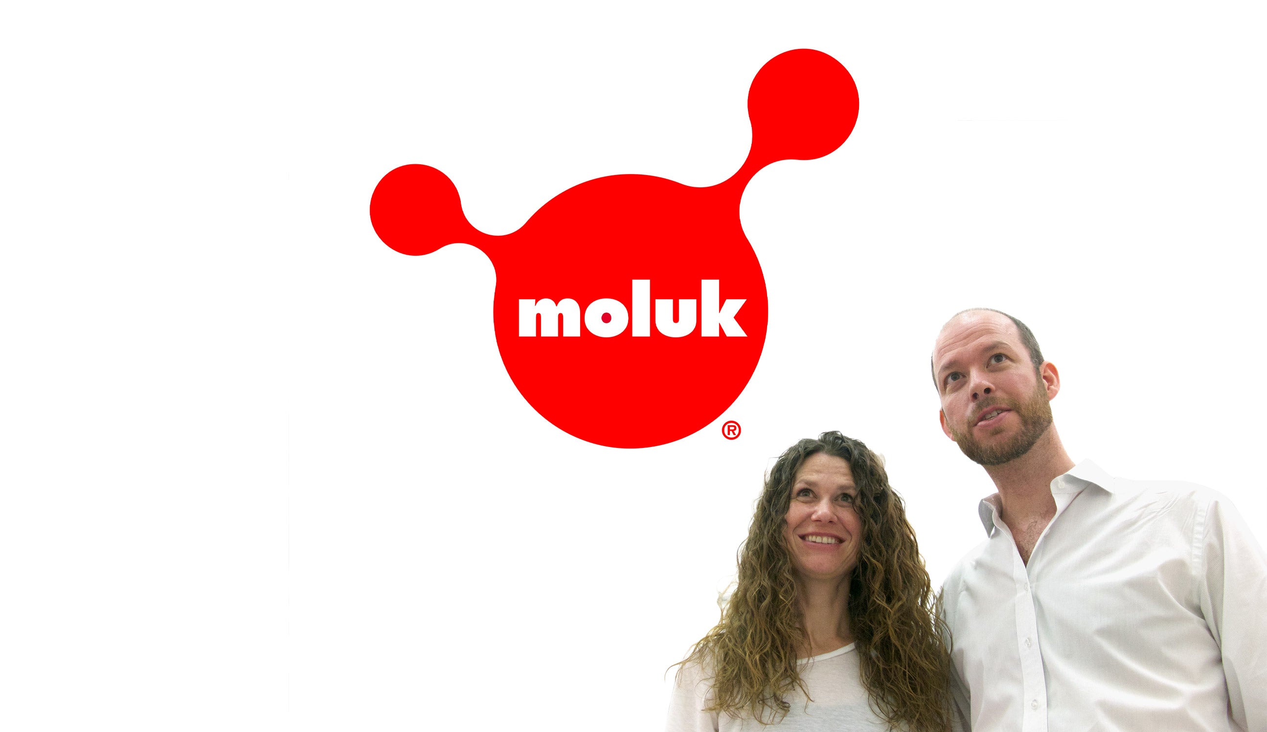 MOLUK founders Alex and Doris Hochstrasser in front of a large red MOLUK logo.