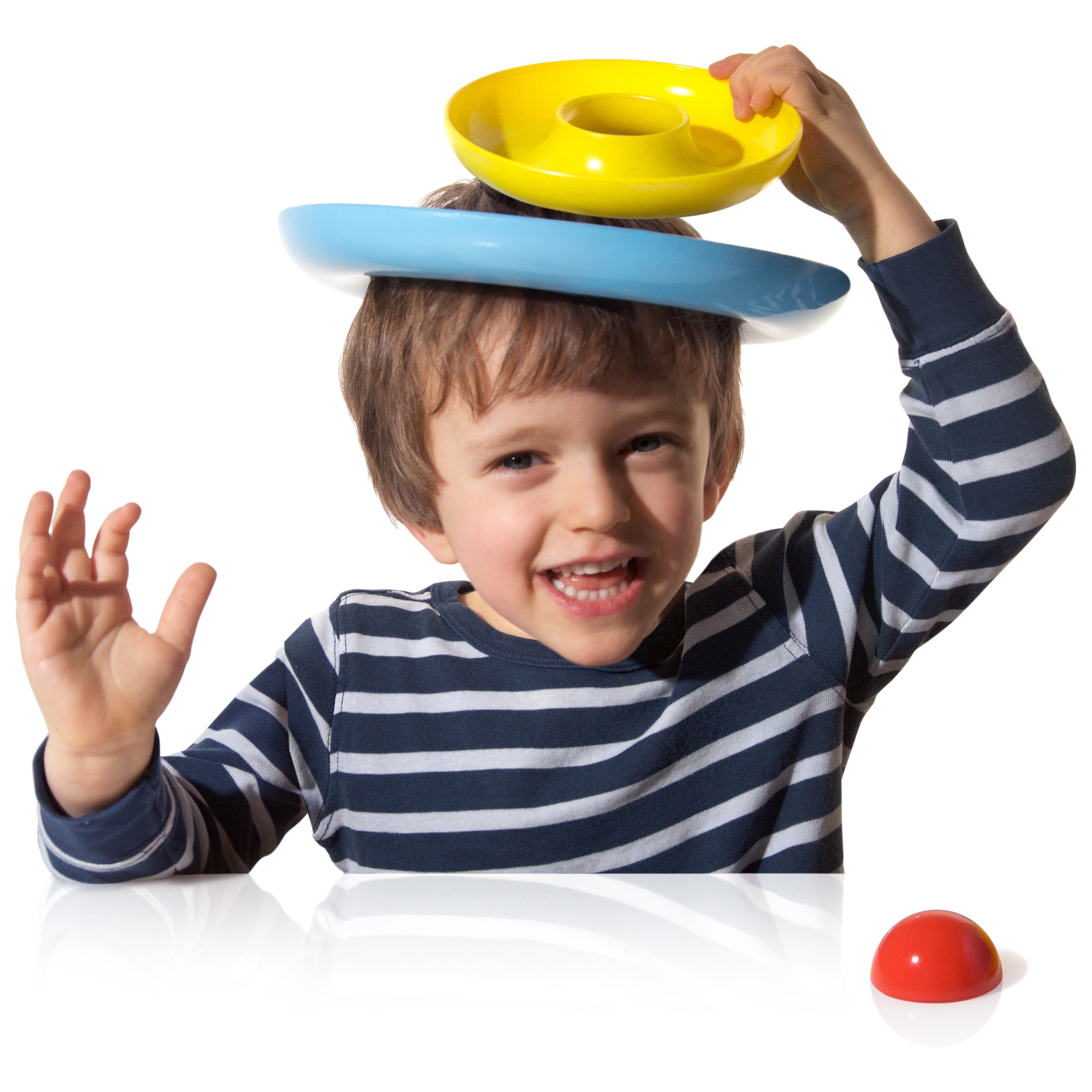 Child balancing two colorful Nello rings by MOLUK on his head.