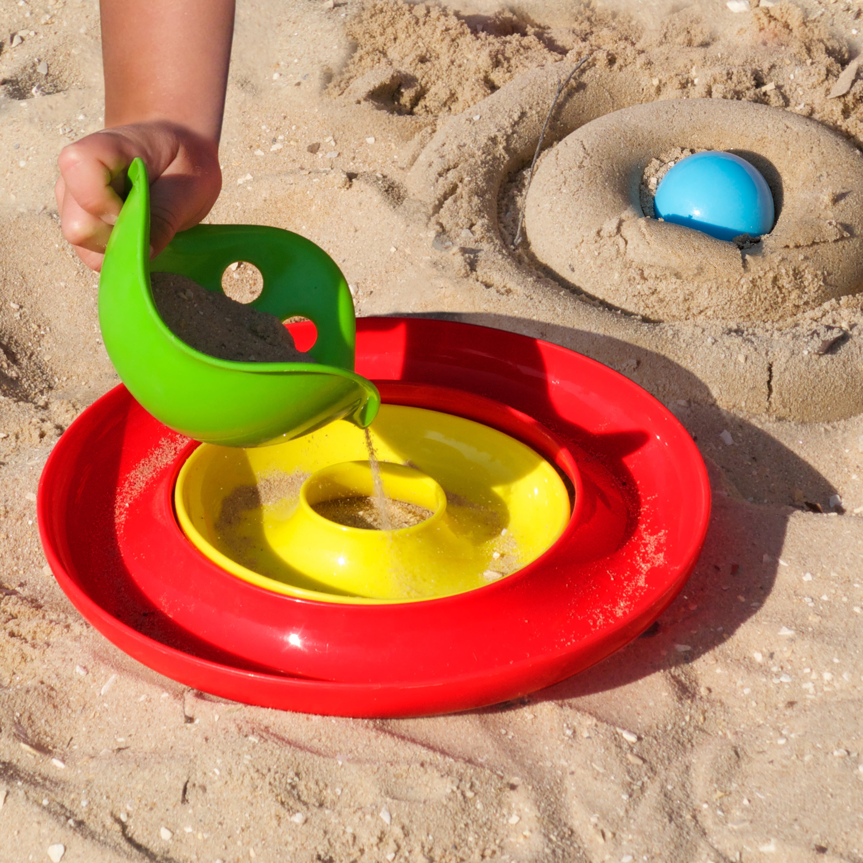 Colorful open-ended Nello rings and Bilibo Mini sand toys.