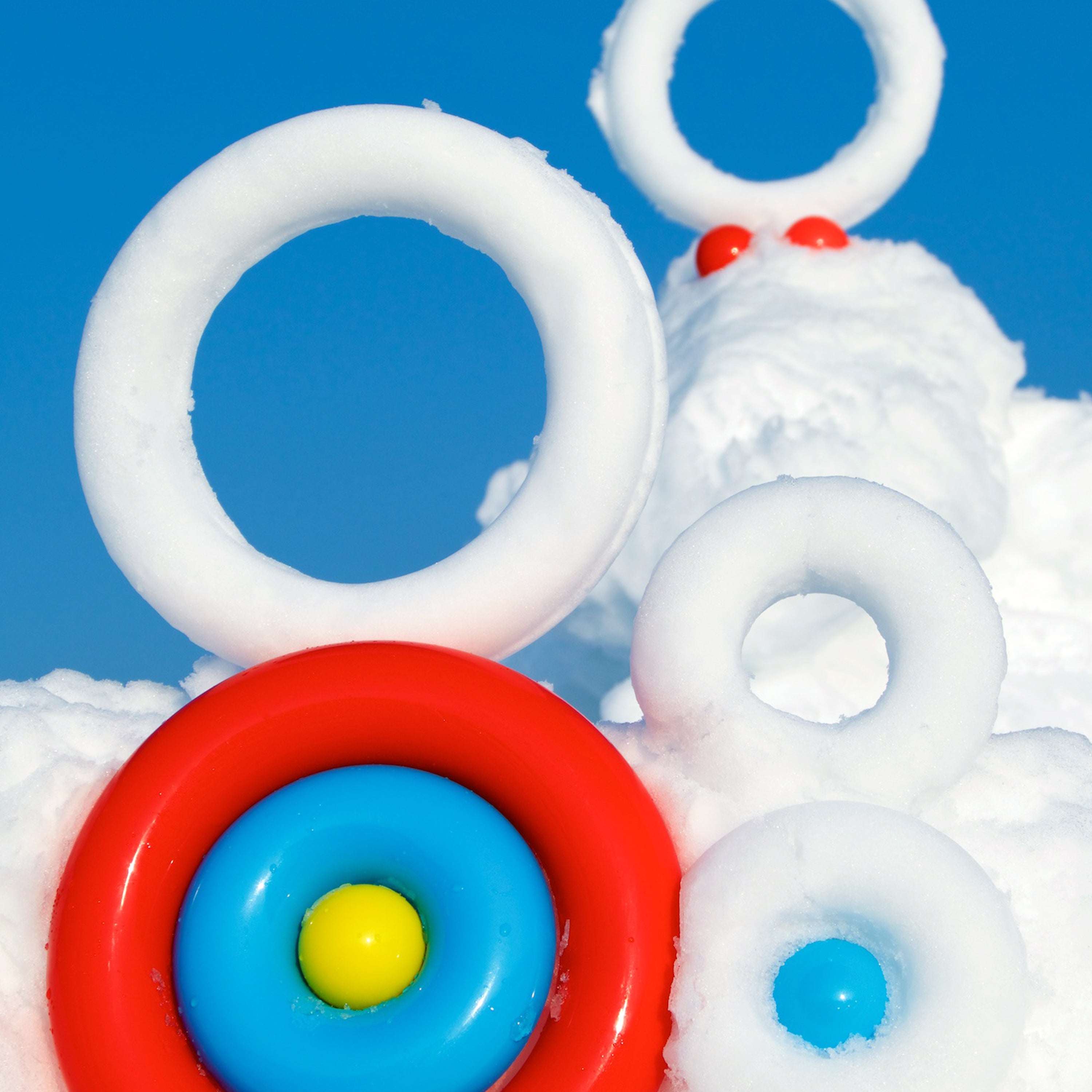 Colorful Nello rings forming donuts of snow, versatile MOLUK toy for outdoor play in winter.