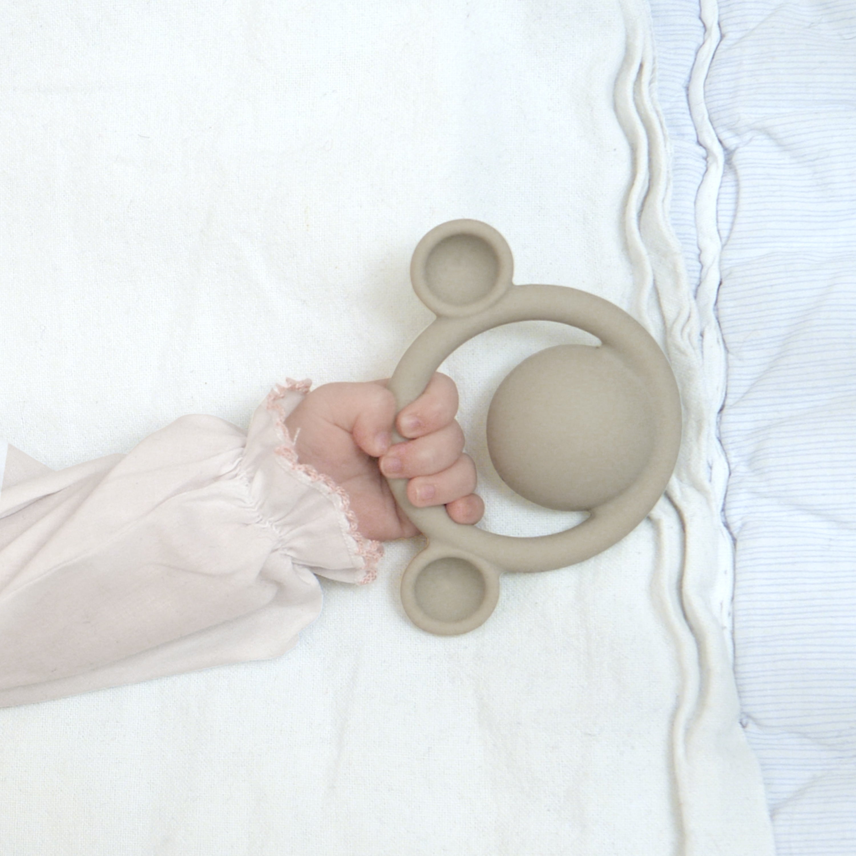 A baby’s hand grasping a Nogi teething ring by MOLUK
