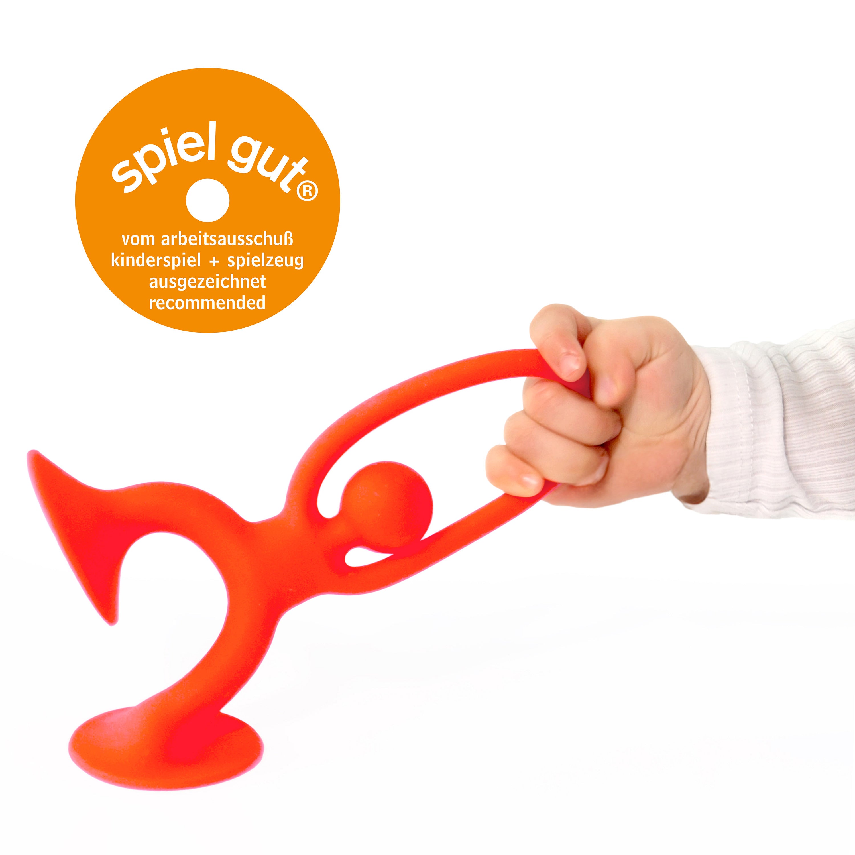 Child’s hand stretching red Noogi silicone toy by MOLUK, shown with spiel gut® award badge for outstanding design and play value.