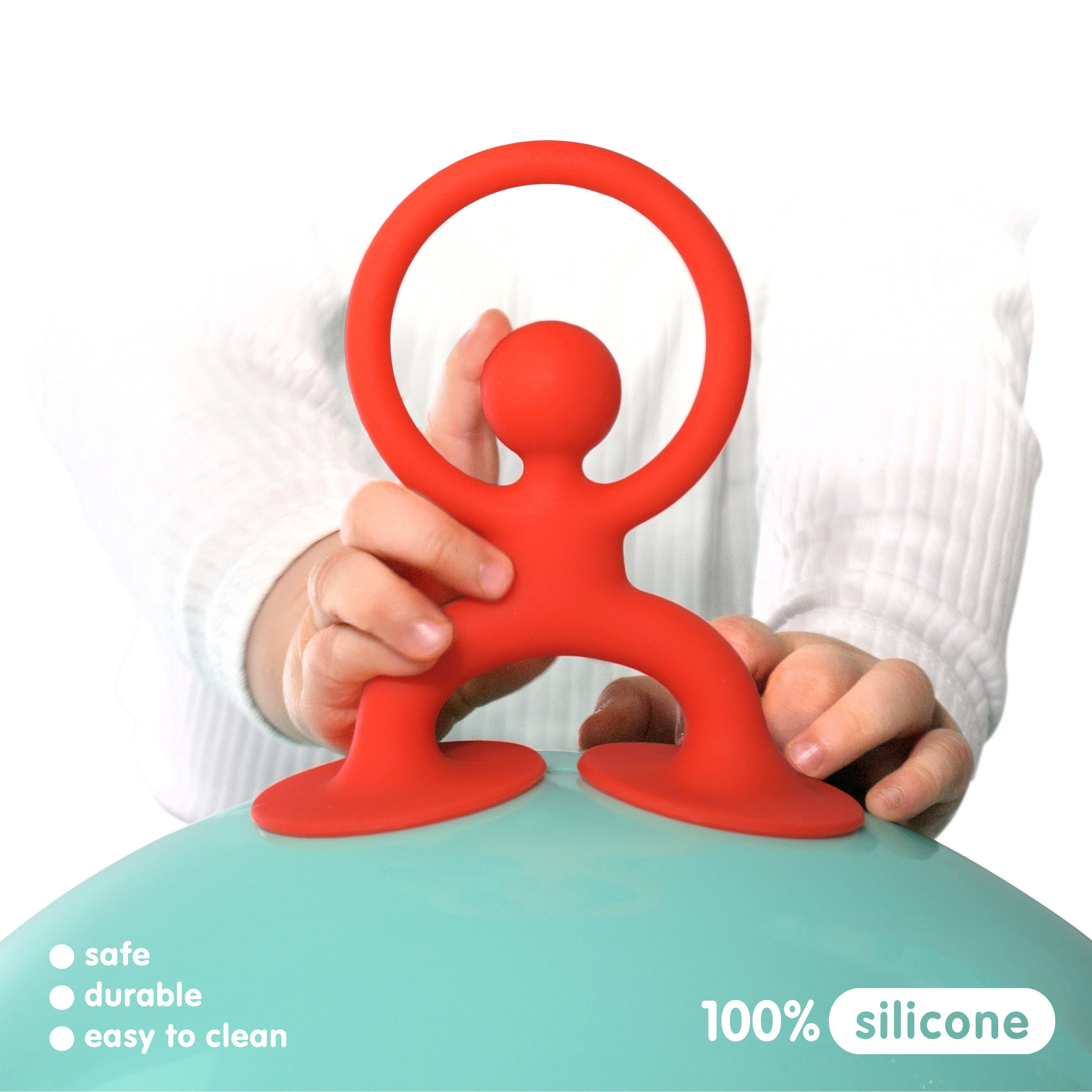 Child holding red Noogi silicone toy by MOLUK with suction feet attached to a mint Bilibo shell, highlighting safe, durable, and easy-to-clean design.