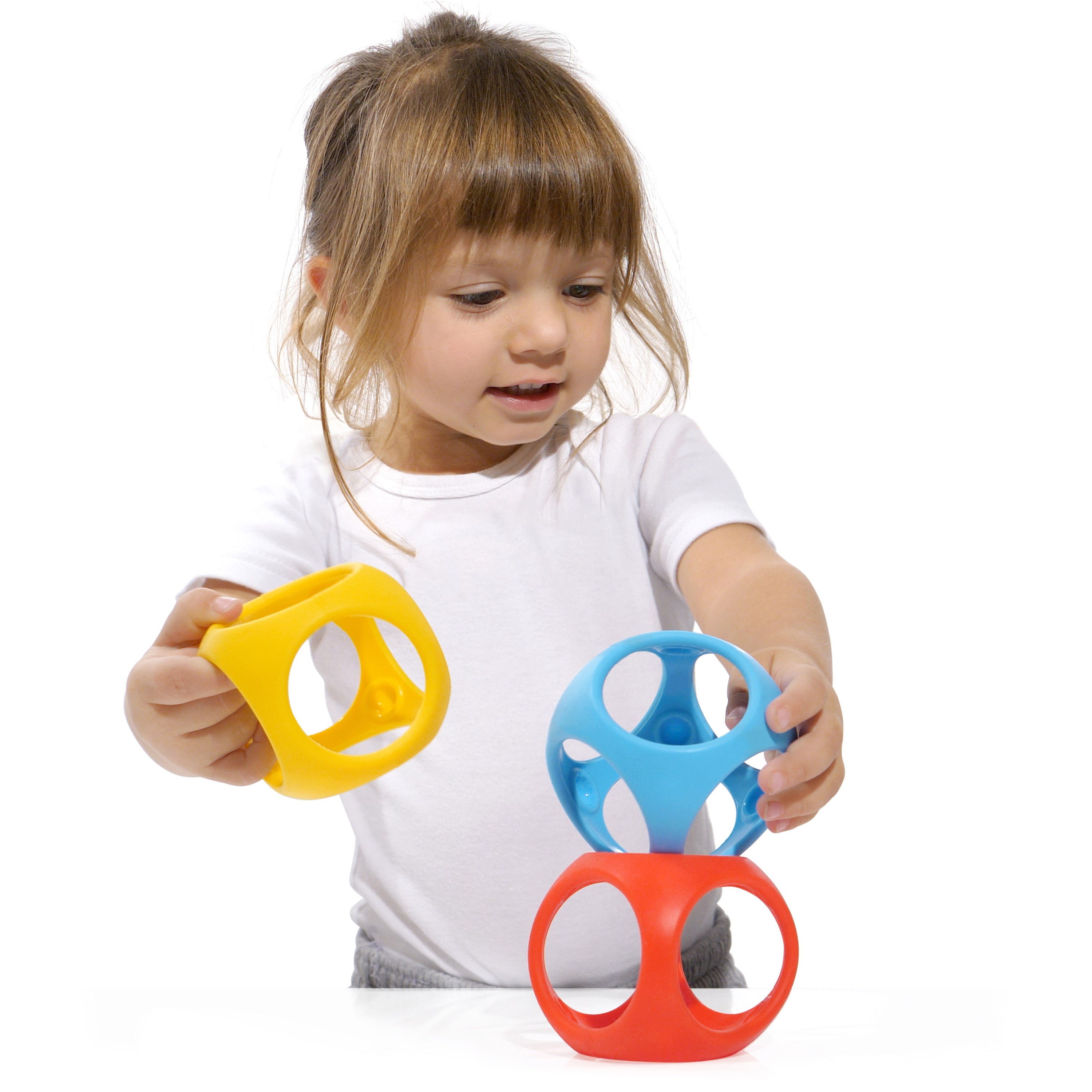 Girl stacking MOLUK’s Oibo silicone cubes in red, blue, and yellow, exploring open-ended building and sensory play.