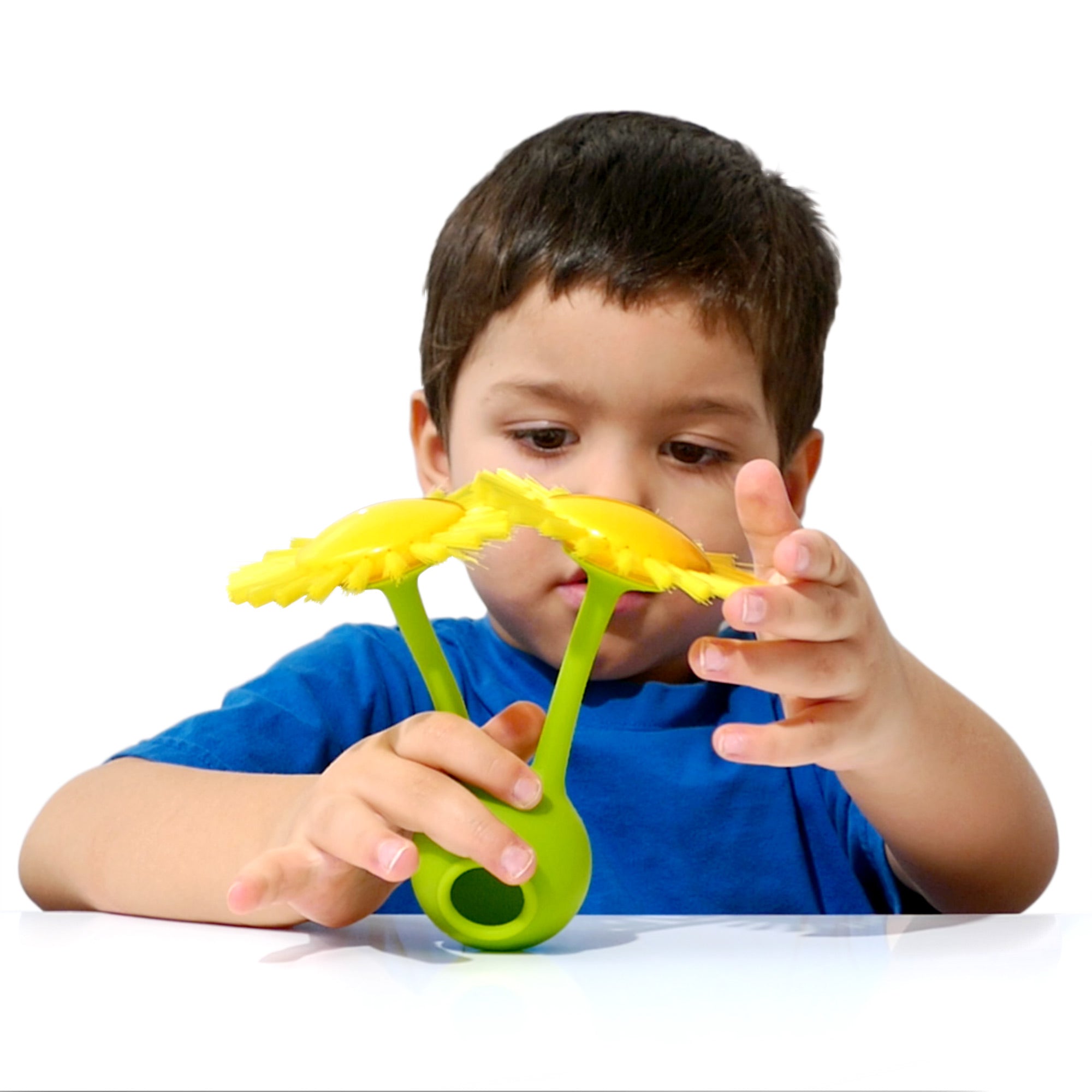 Boy playing with a green Oogi Bongo by MOLUK with two Sunny brushes attached forming a sensory flower.