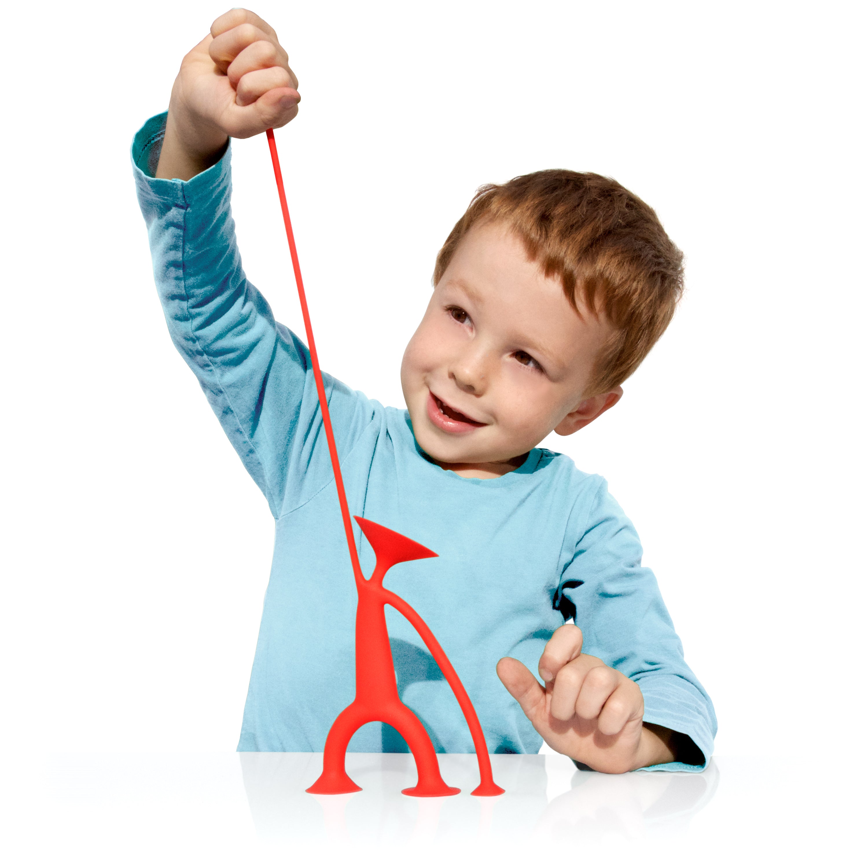 Boy playing with a red Oogi suction cup fidget toy by MOLUK, pulling and stretching the elastic arm of the figure.