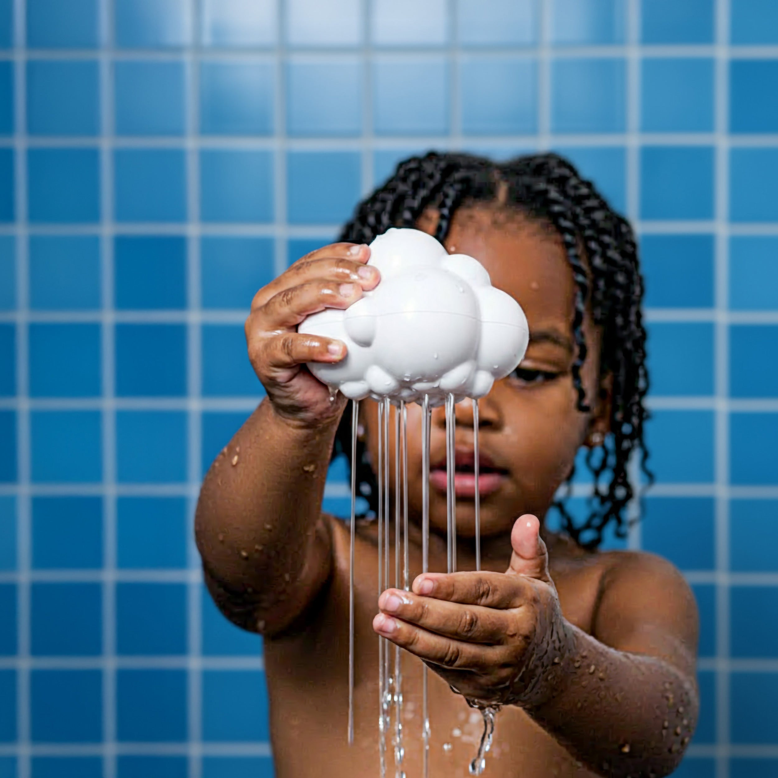 Child playing with the Pluï Rain Cloud bath toy by MOLUK gently pouring water