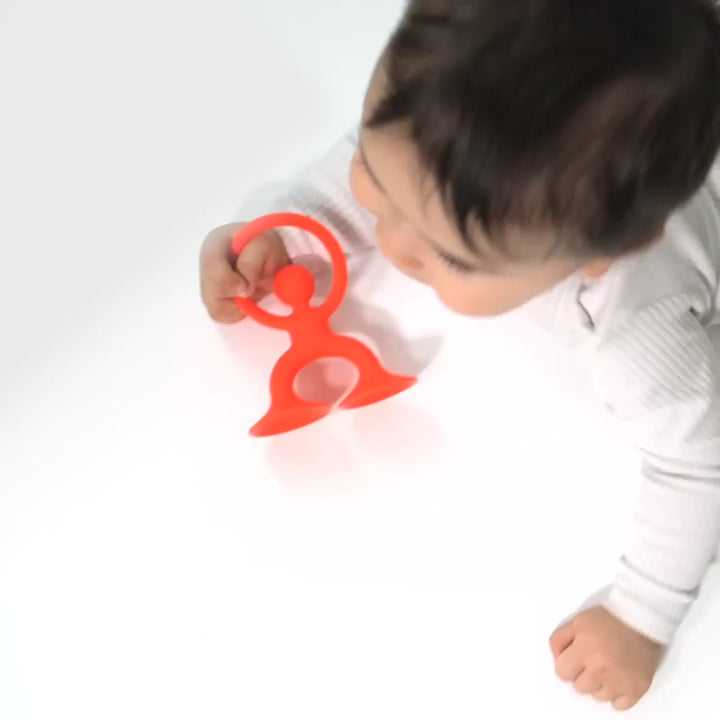 Video showing Noogi by MOLUK – a flexible silicone figure with suction cups –being grasped, stretched and chewed.