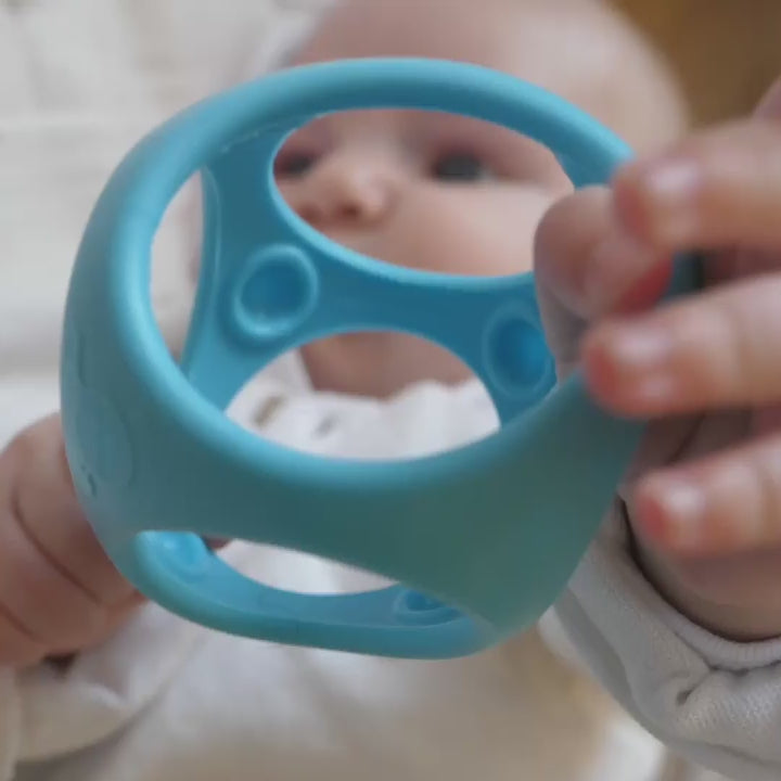 Video showing MOLUK's Oibo sensory building blocks in action with children grasping, chewing, rolling, stacking, throwing, and catching the elastic cubes.