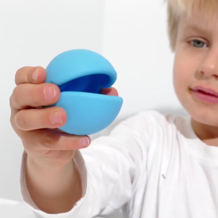 Video showing Mox by MOLUK – a silicone sensory ball with a big mouth – being squeezed, stacked, rolled, and used for imaginative play, speech exercises, and simple games with children.