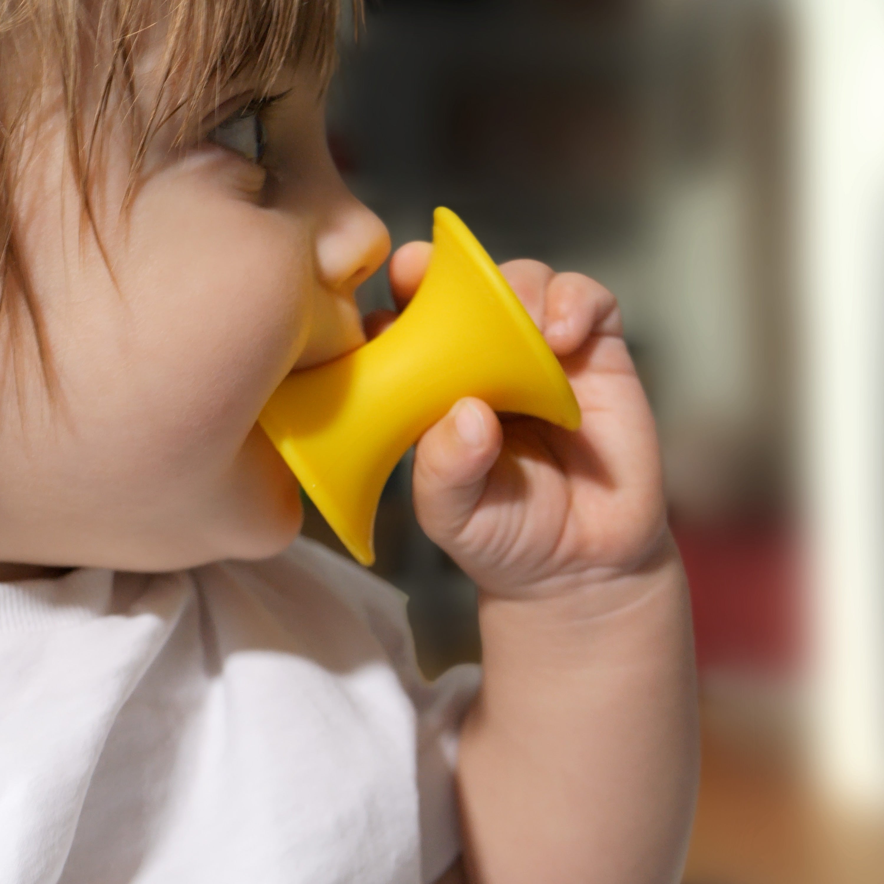Baby chewing on a yellow Tulu silicone building block by MOLUK, exploring its safe tactile shape during teething play.