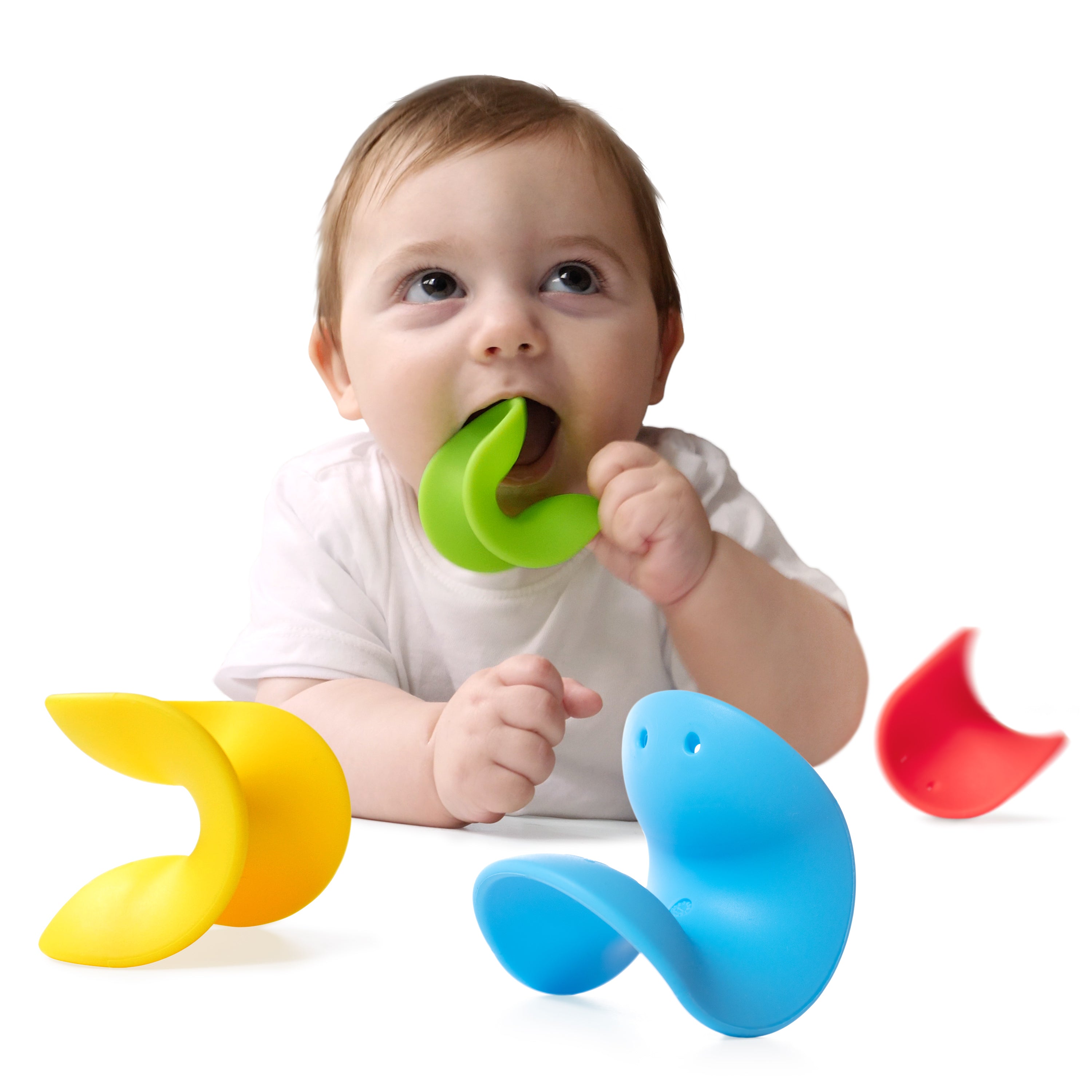 Baby chewing on a green silicone Ulu teething toy by MOLUK with other Ulu pieces in blue, red and yellow wobbling around.