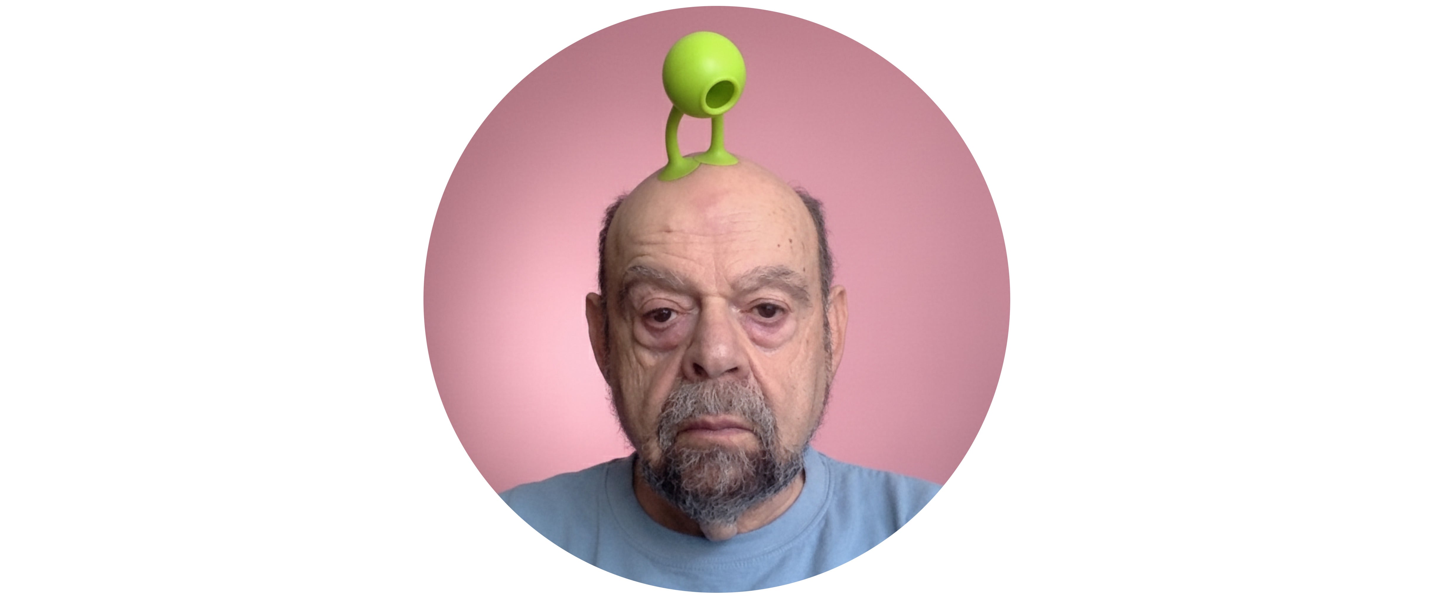 Bernie DeKoven balancing a green Oogi Bongo on his head, perfectly embodying the spirit of play.