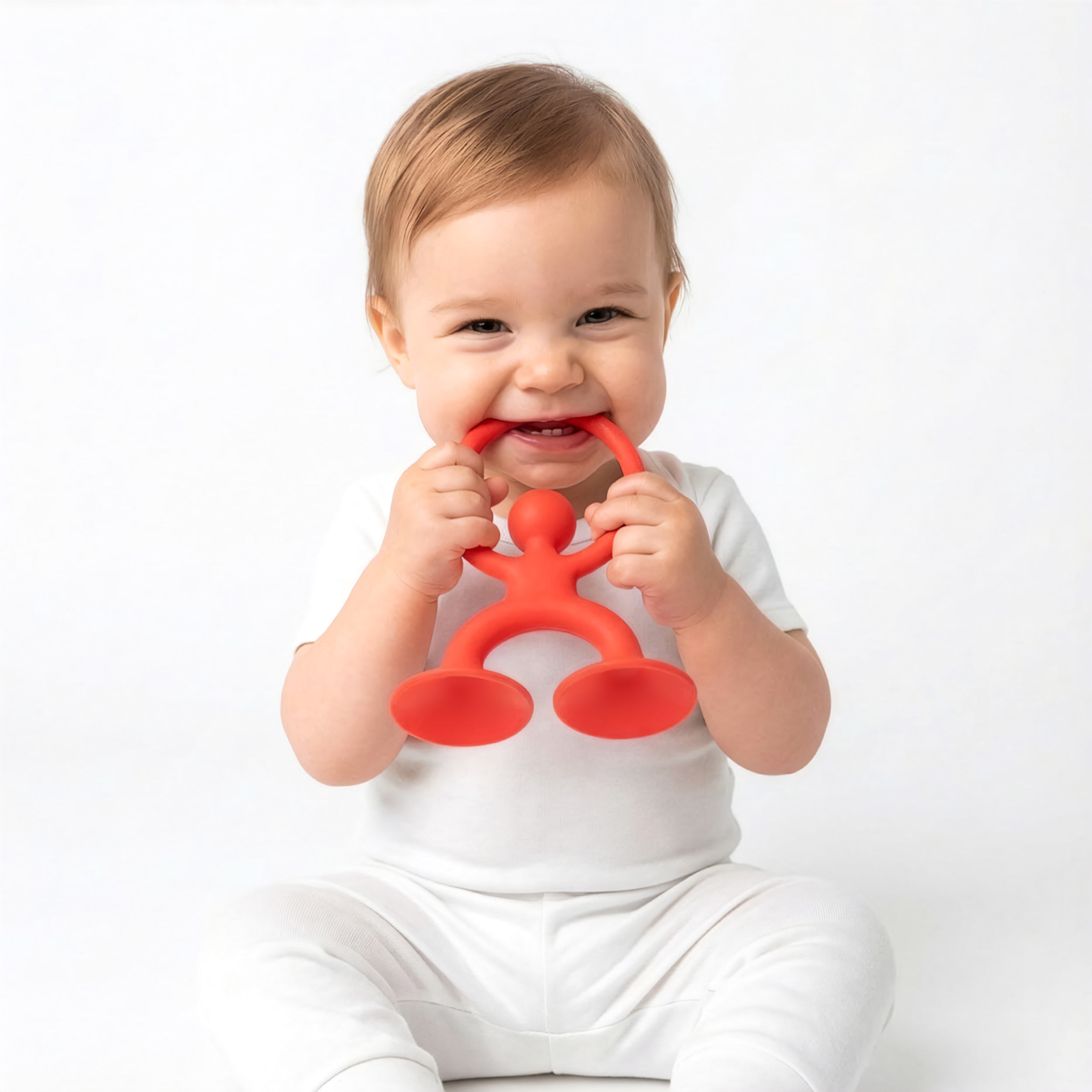 Baby chewing on MOLUK’s red Noogi silicone teething and grasping toy