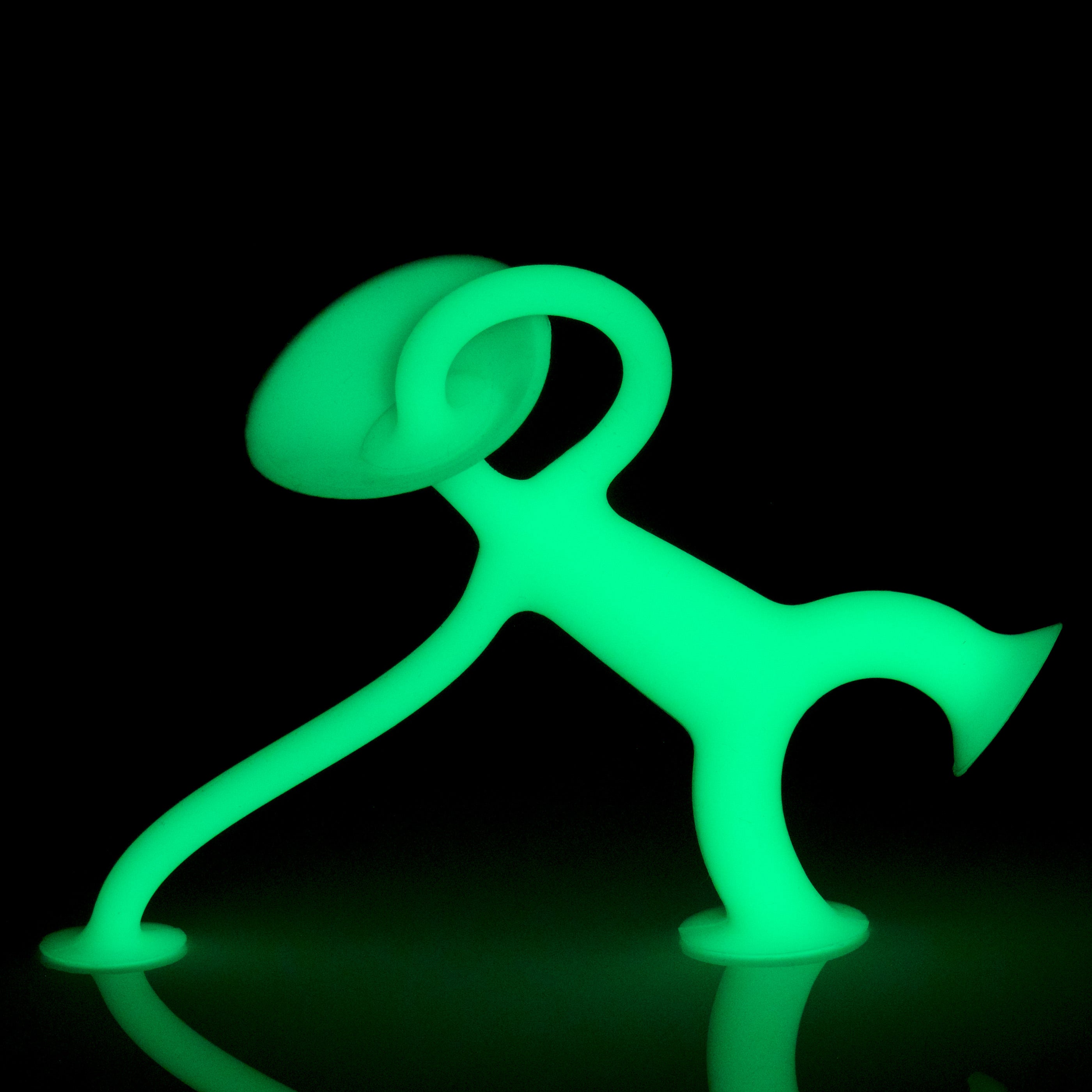 Oogi Junior GLOW by MOLUK, a pocket-sized suction cup fidget figure, is shown glowing at night.