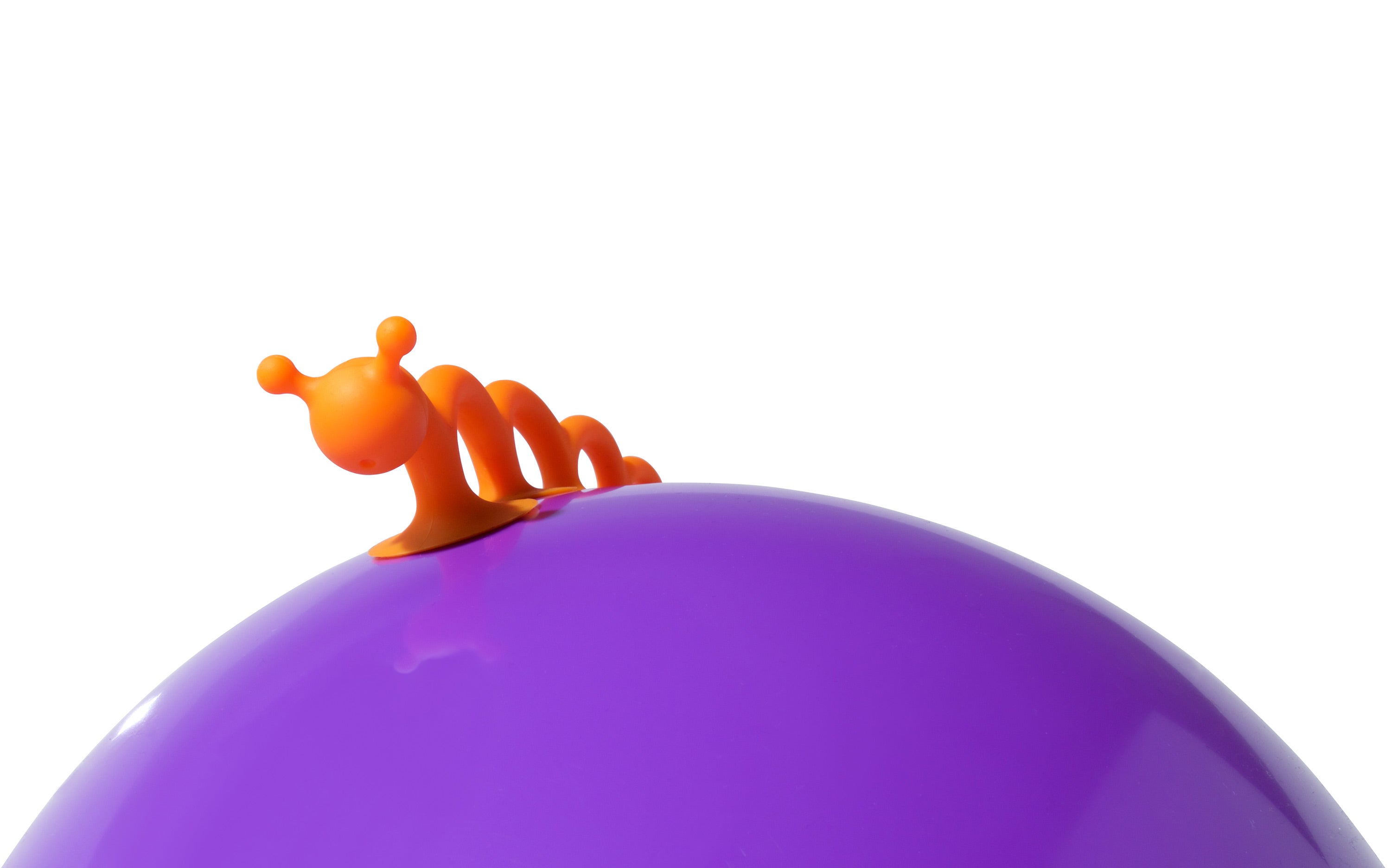 Orange Oogi Pilla by MOLUK, a flexible orange silicone creature with suction cups, attached to a purple Bilibo play shell.