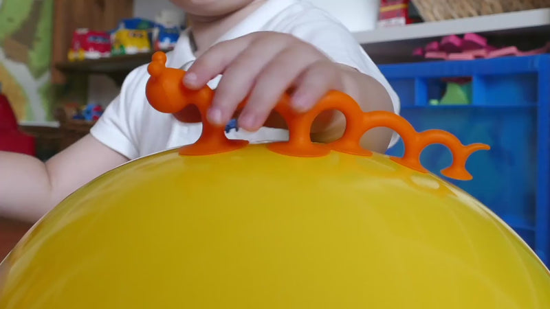 Video showing Oogi Pilla by MOLUK – a flexible orange silicone creature with suction cups – stretching, sticking to smooth surfaces, wiggling like a caterpillar, and used as a sensory fidget toy.