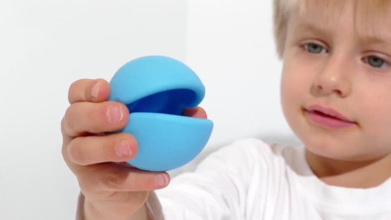 Video showing Mox by MOLUK – a silicone sensory ball with a big mouth – being squeezed, stacked, rolled, and used for imaginative play, speech exercises, and simple games with children.