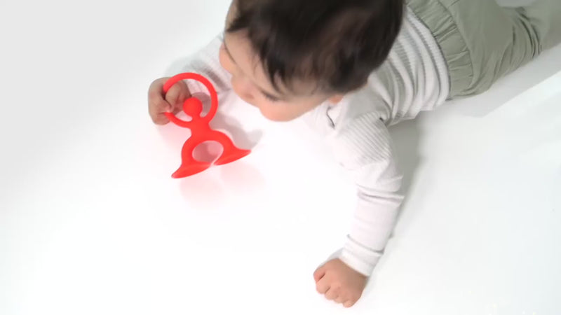 Video showing Noogi by MOLUK – a flexible silicone figure with suction cups –being grasped, stretched and chewed.
