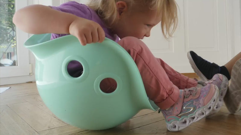 Video of children playing with Bilibo by MOLUK, rocking, spinning, and balancing in colorful shell-shaped seats indoors and outdoors.