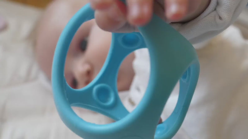 Video showing MOLUK's Oibo sensory building blocks in action with children grasping, chewing, rolling, stacking, throwing, and catching the elastic cubes.